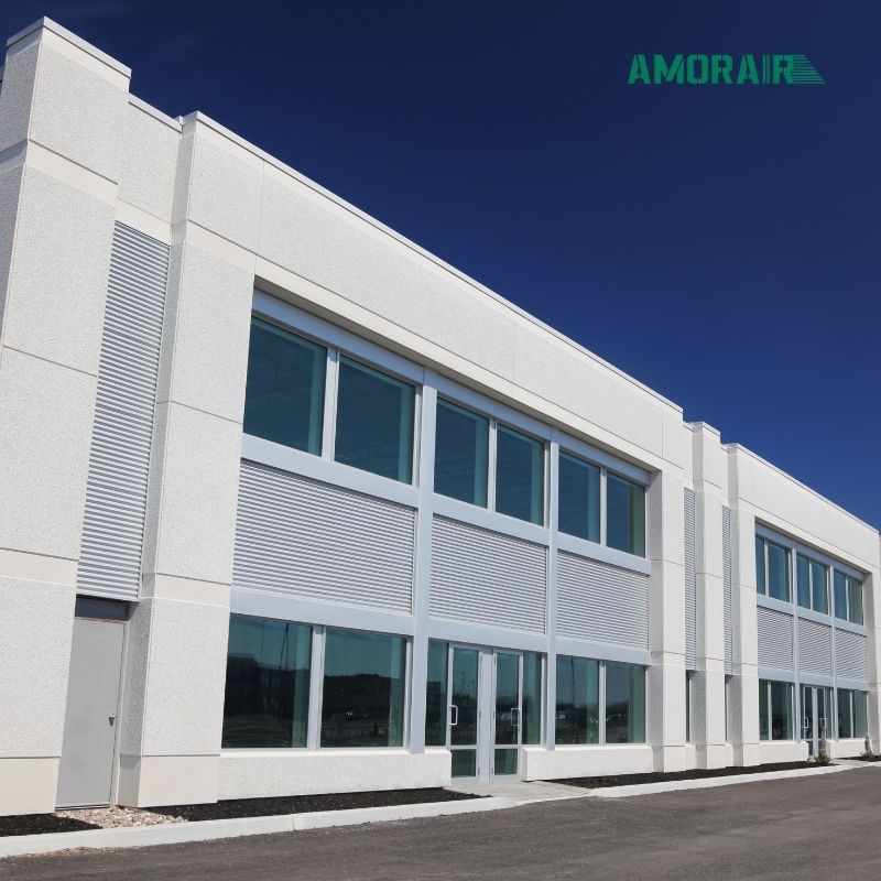 Modern building exterior with glass windows and a clear blue sky, featuring the AmorAir logo.