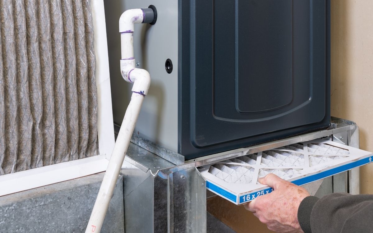Person replacing an air filter on a heating and cooling system.