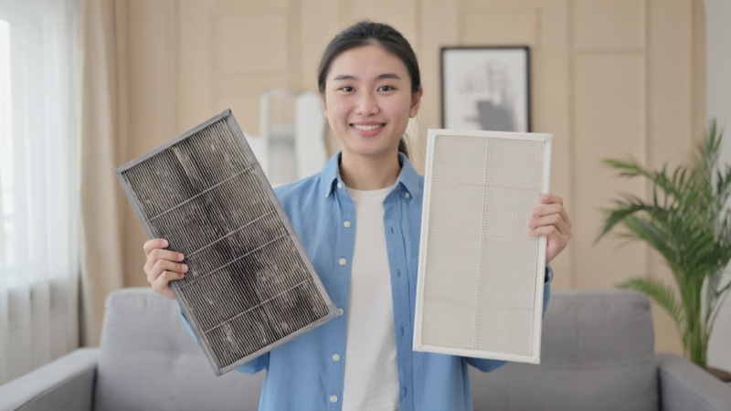Person holding two air filter frames in a living room setting